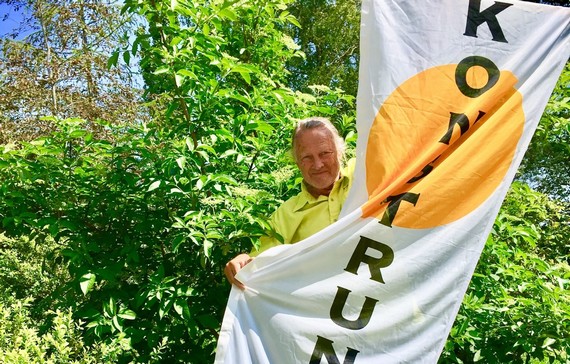 Konstnären Rurik står och håller i en flagga med texten Konst runt Omberg.
