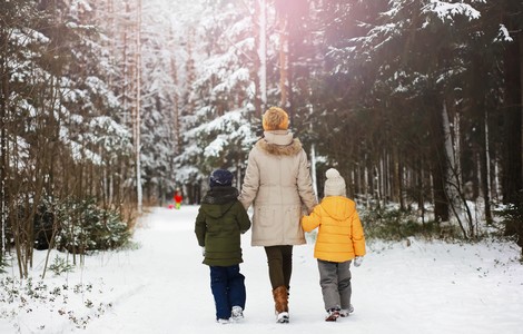 En familj, en mamma och två barn som går i skogen under vintertid. 