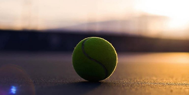 En tennisboll som ligger på en bana. 